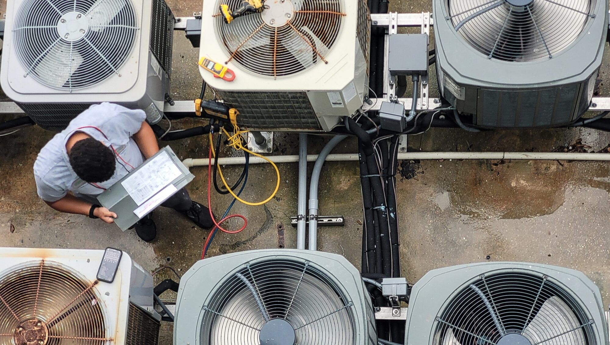 HVAC technician reviewing paperwork among rooftop condenser units