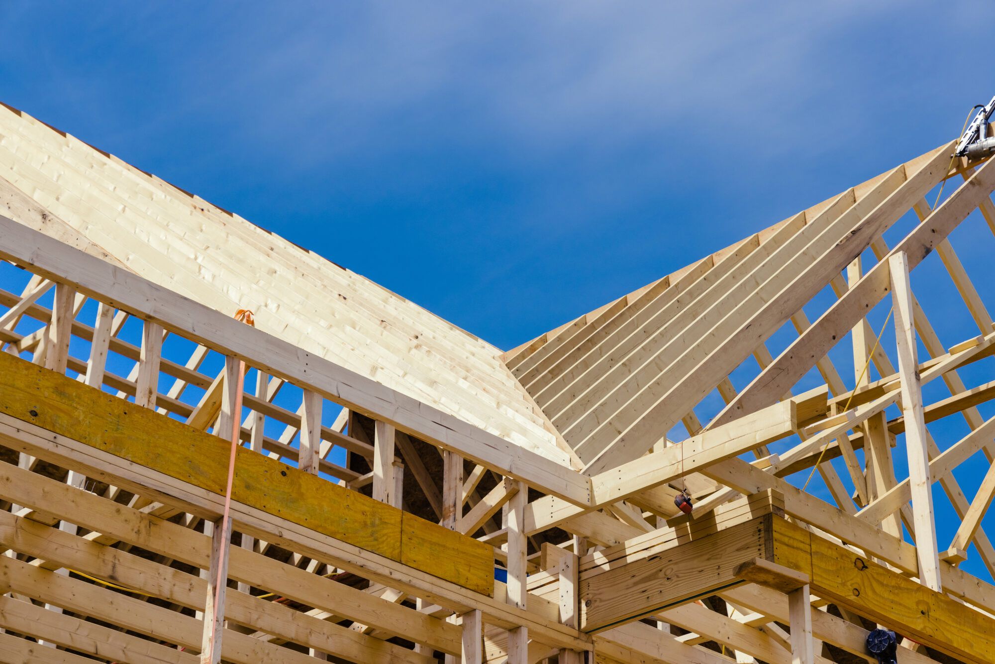 New residential roof framing against a blue sky