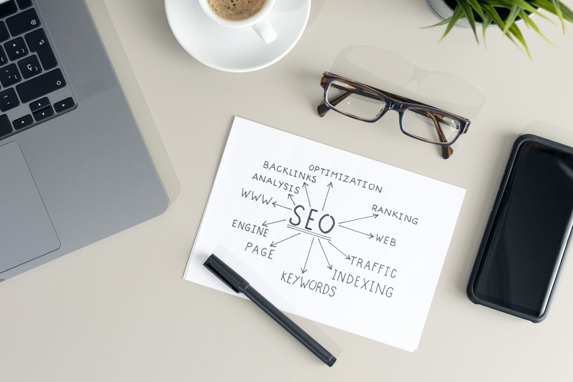 Desk with an SEO planning sketch, glasses and a phone