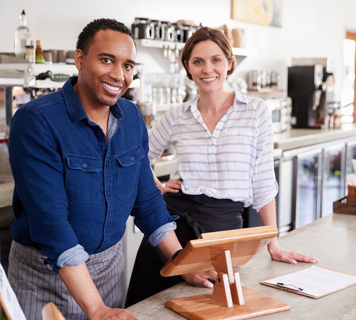 Two small business owners smiling behind their counter
